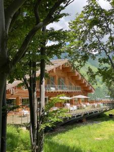 a log building with tables and umbrellas in the trees at Chalet Morel 1586 Hotel & Spa in Limone Piemonte