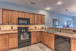 a kitchen with wooden cabinets and a black stove top oven at Idyllic Camdenton Condo with Community Pool and Lake! in Camdenton