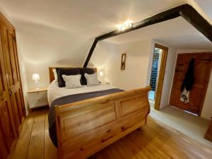 a bedroom with a wooden bed in a room at Beautiful Character 5 Bedroom Dorset Thatched Cottage - Great Location - Garden - Parking - Fast WiFi - Smart TV - Newly decorated - sleeps up to 10! Only 18 mins drive to Sandbanks Beach! Close to Bournemouth & Poole in Wimborne Minster
