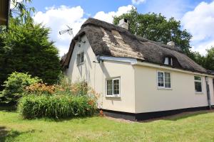 a thatch roof house with a garden at Beautiful Character 5 Bedroom Dorset Thatched Cottage - Great Location - Garden - Parking - Fast WiFi - Smart TV - Newly decorated - sleeps up to 10! Only 18 mins drive to Sandbanks Beach! Close to Bournemouth & Poole in Wimborne Minster