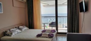 a bedroom with a bed and a view of a balcony at Апартаменти и студия в комплекс Акротирия in Nesebar