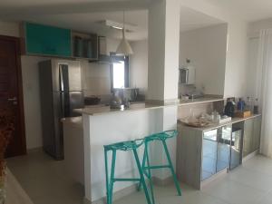 a kitchen with two green bar stools and a refrigerator at Praia do Forte- Iberostar- Ap Luxuoso 3 qts in Mata de Sao Joao +2 photos