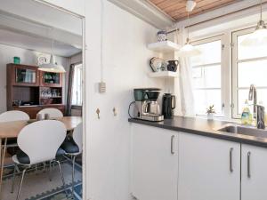 eine Küche mit einem Waschbecken und einem Tisch mit Stühlen in der Unterkunft 3 person holiday home in r sk bing in Ærøskøbing