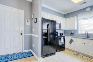 a kitchen with a black refrigerator and white cabinets at Coastal Escape in Myrtle Beach