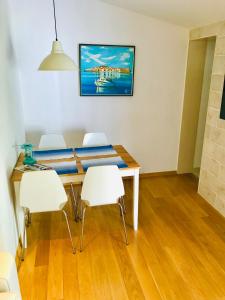 a dining room with a table and white chairs at Apartments Paola in Makarska