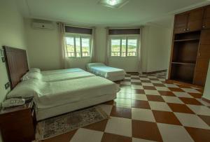 1 dormitorio con 2 camas y suelo a cuadros en Motel Gzenaya, en Tánger