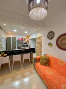 ein Wohnzimmer mit einem orangenen Sofa und einer Küche in der Unterkunft Casa Maragogi in Maragogi