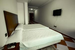 een slaapkamer met 2 bedden en een tv aan de muur bij Motel Gzenaya in Tanger