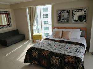 a bedroom with a bed and a couch and a window at River View Suites Guayaquil in Guayaquil