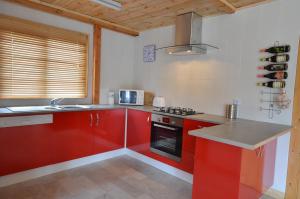 una cucina con armadi rossi e un piano cottura. di Woodlands Cottage a Treignac