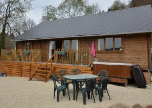 a table and chairs in front of a log cabin at Woodlands Cottage in Treignac