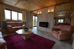 uma sala de estar com sofás, uma mesa e uma televisão em Woodlands Cottage em Treignac