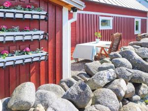 a backyard with a table and rocks next to a red shed at 6 person holiday home in S LVESBORG in Sölvesborg