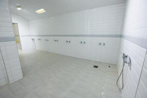 un baño grande con paredes de azulejos blancos y duchas. en Motel Gzenaya, en Tánger