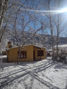 a yellow building in the snow with a tree at Cabaña Pura Vida in Potrerillos +12 photos