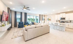 a living room with a couch and a kitchen at Serene Vibrant 4 Bdrm Villa with Games Room at Encore in Orlando