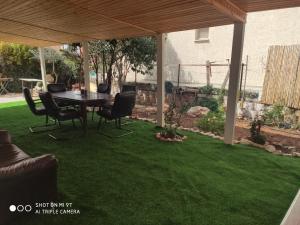 eine Terrasse mit einem Tisch und Stühlen auf Gras in der Unterkunft גני התניא in Safed