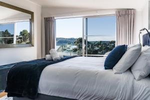 a bedroom with a large bed with a large window at Government House in Raglan