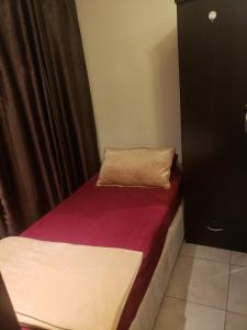 een kleine kamer met een bed en een gordijn bij Hostel Dubai in Dubai