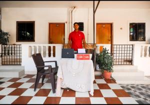 Un homme debout à côté d'une table avec un ordinateur portable dans l'établissement Rosy Guest House, à Calangute