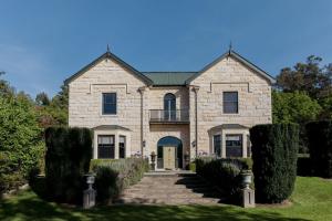 Casa de piedra grande con porche y balcón. en Casa Nova House, en Oamaru