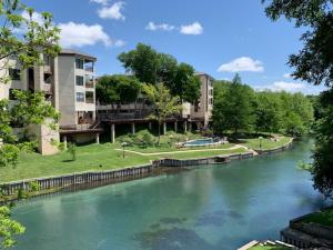 a view of a river with buildings in the background at Inverness Condos Comal River IC 216 in New Braunfels