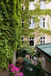 ein mit Efeu bedecktes Gebäude mit Blumen davor in der Unterkunft Hotel Schwalbe in Wien