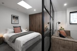Apartments on Moray في دنيدن: غرفة نوم بسرير كبير وأريكة