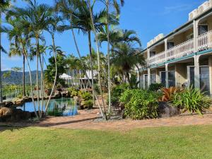 a resort with a swimming pool and palm trees at Colonial Palms Motor Inn in Airlie Beach