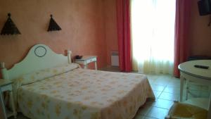 a bedroom with a white bed and a window at Hotel Les Cavalets in Bauduen