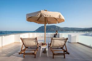 a patio with two chairs and an umbrella on a roof at Royal Bay Suites in Kefalos