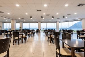 a dining room with tables and chairs and windows at Royal Bay in Kefalos