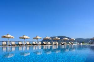 a swimming pool with chairs and umbrellas at Royal Bay Suites in Kefalos