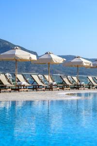 a group of lounge chairs and umbrellas on a beach at Royal Bay Suites in Kefalos
