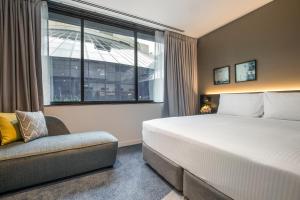 een slaapkamer met een bed, een stoel en een raam bij Crowne Plaza Melbourne, an IHG Hotel in Melbourne