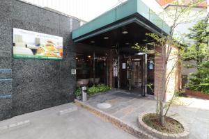 ein Gebäude mit einem Baum davor in der Unterkunft Hotel Green Arbor in Sendai
