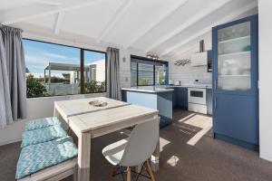 uma cozinha com uma mesa de madeira e um armário azul em The Blue Beach House em Mount Maunganui