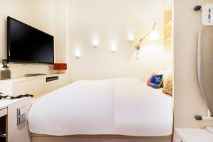 a white room with a bed and a flat screen tv at The Daulat by Hotel Calmo in Singapore
