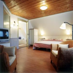 a bedroom with a bed and two chairs and a tv at Hotel Vesting Bourtange in Bourtange