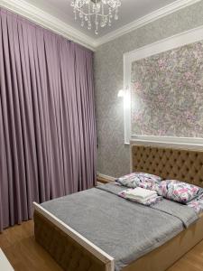 a bedroom with a bed with purple curtains and a chandelier at Гостиница АСКАР in Shymkent