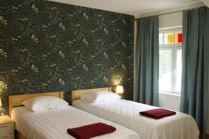 1 dormitorio con 2 camas y pared con papel pintado con motivos florales en Posti Villa, en Võsu
