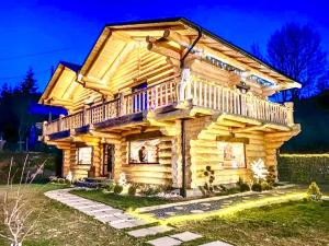 a log cabin with a wrap around deck at night at The Mountain's Sea Chalet in Colibiţa