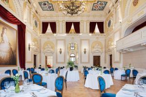 um salão de banquetes com mesas brancas e cadeiras azuis em Áurea Ana Palace by Eurostars Hotel Company em Budapeste