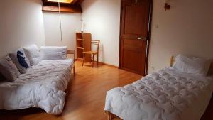 a bedroom with two beds and a chair in it at Maison au cœur des Pyrénées in Perles-et-Castelet