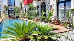 a courtyard with a swimming pool with chairs and plants at Dmira Alacati in Alaçatı