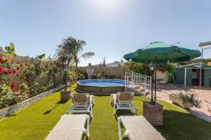 a patio with two chairs and an umbrella and a pool at Casita Puente Viejo in Nerja