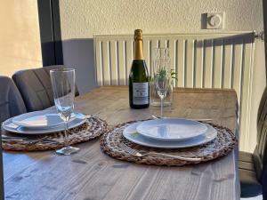 a wooden table with a bottle of wine and glasses at ParaLodge in Saint-Vincent-les-Forts