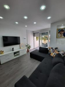 ein Wohnzimmer mit einem schwarzen Sofa und einem Flachbild-TV in der Unterkunft Vice in Omiš