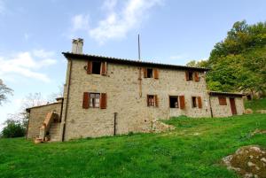 ein altes Steinhaus auf einem grasbewachsenen Hügel in der Unterkunft A stay surrounded by greenery - Agriturismo La Piaggia -app 3 guests in Vivo dʼOrcia