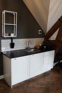 een keuken met witte kasten en een wastafel bij Boetiekhotel Ons Oude Raadhuis digitaal inchecken in Hooge Zwaluwe